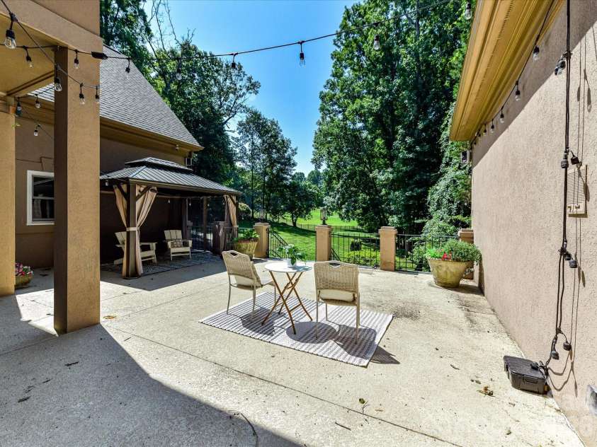 4725 Old Course Drive, Charlotte, NC 28277.  MLS# CAR4384171, YatesRealty ID 28405. The spacious patio offers an inviting setting for outdoor entertaining and relaxation, complete with a covered gazebo, café lighting, and peaceful views of the lush, private backyard.