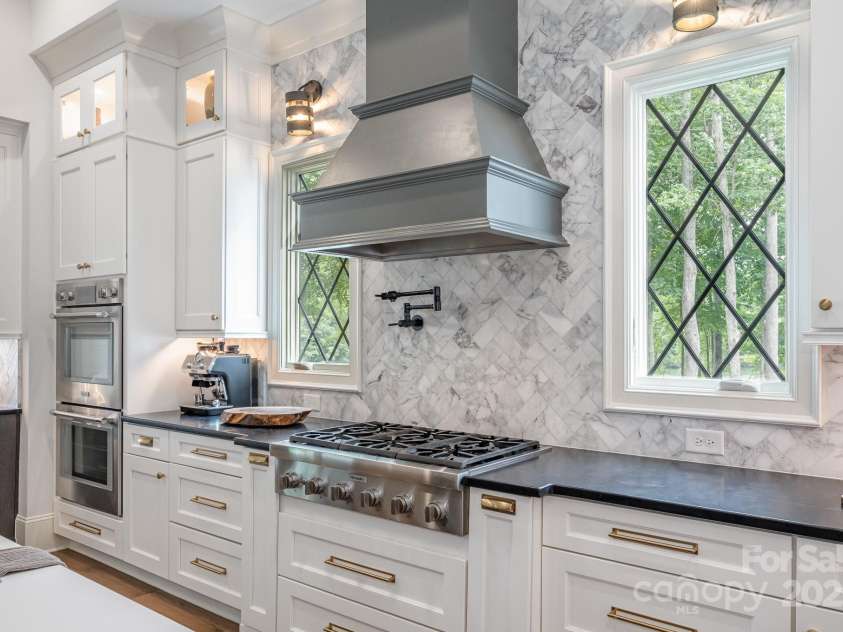 708 Amalfi Drive, Davidson, NC 28036.  MLS# CAR4281253, YatesRealty ID 28511. Six burner professional range with pot filler flanked by slender casement windows provides a stunning focal point in the exquisite kitchen.