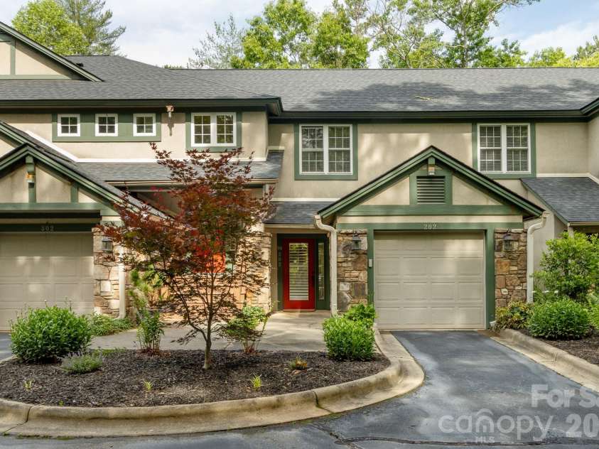 99 Ridgetop Circle, Brevard, NC 28712.  MLS# CAR4387560, YatesRealty ID 28540. Front Exterior / Building View – Attractive mountain-style condominium exterior featuring stone accents, manicured landscaping, private garage, and low-maintenance living in a peaceful wooded setting.