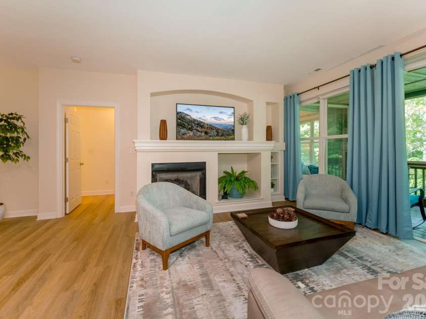 99 Ridgetop Circle, Brevard, NC 28712.  MLS# CAR4387560, YatesRealty ID 28540. Living Room with Fireplace & Screened Porch Access – Spacious living area featuring a cozy gas fireplace, built-in architectural details, and seamless access to the screened porch overlooking peaceful wooded surroundings.