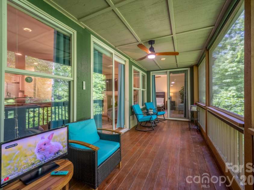 99 Ridgetop Circle, Brevard, NC 28712.  MLS# CAR4387560, YatesRealty ID 28540. Screened Porch Overlooking Woods – Expansive screened porch perfect for outdoor living, featuring wooded privacy, ceiling fan, and multiple seating areas to enjoy the peaceful surroundings.