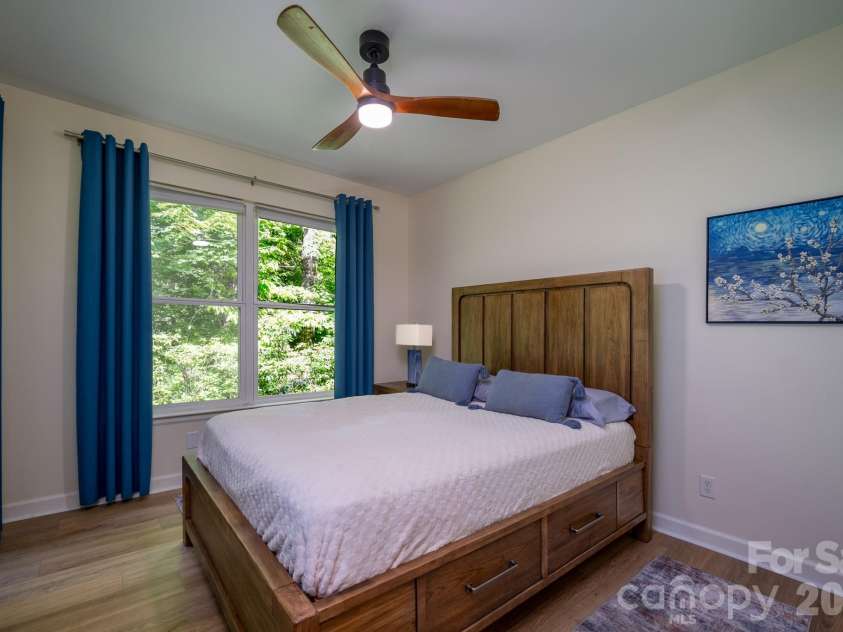 99 Ridgetop Circle, Brevard, NC 28712.  MLS# CAR4387560, YatesRealty ID 28540. Spacious Guest Bedroom Retreat – Generously sized guest bedroom featuring luxury vinyl plank flooring, modern ceiling fan, and direct access to the screened porch for peaceful wooded views.