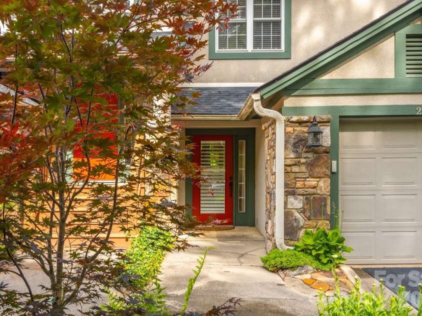 99 Ridgetop Circle, Brevard, NC 28712.  MLS# CAR4387560, YatesRealty ID 28540. Welcoming Entry Approach – Inviting covered entrance highlighted by beautiful stonework, mature landscaping, and a vibrant entry door creating warm curb appeal.