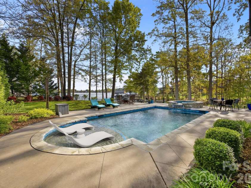 20727 Pointe Regatta Drive, Cornelius, NC 28031.  MLS# CAR4370865, YatesRealty ID 28632. Private backyard features an in-ground pool with sun shelf, spa, expansive patio, and mature trees with water views.