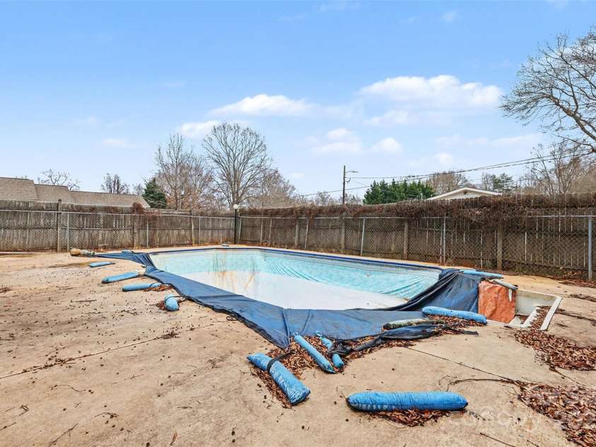 119 Moore Drive, Gastonia, NC 28056.  MLS# CAR4332115, YatesRealty ID 2865. In-ground swimming pool is currently non-operational. The fenced pool area includes a surrounding concrete deck and offers potential for repair, removal, or repurposing according to buyer preference. Sold as-is.