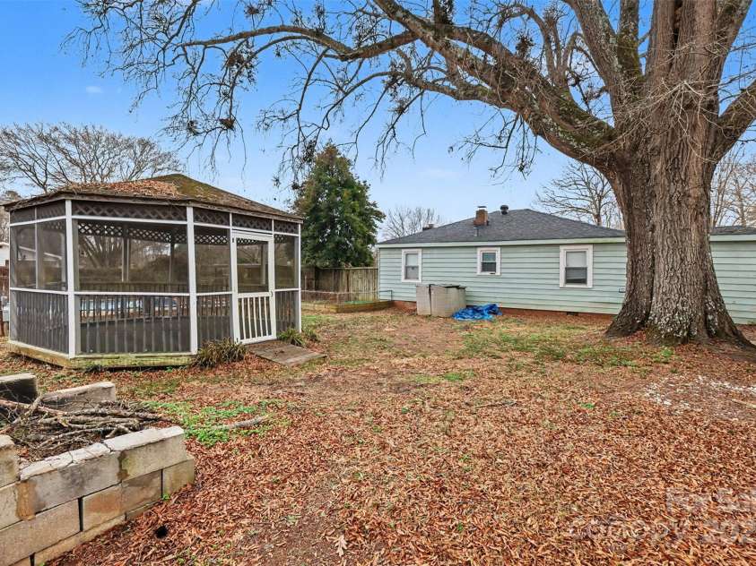 119 Moore Drive, Gastonia, NC 28056.  MLS# CAR4332115, YatesRealty ID 2865. Mature trees provide shade and character, while the open yard offers space for gatherings, gardening, or recreation. A fire pit area adds to the outdoor appeal, creating a cozy setting for evenings with family and friends. T