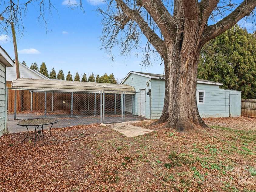 119 Moore Drive, Gastonia, NC 28056.  MLS# CAR4332115, YatesRealty ID 2865. Private backyard featuring mature trees, a detached garage, and a covered carport offering excellent flexibility for parking, storage, or workshop use. The yard provides a shaded outdoor setting with room to relax or enterta
