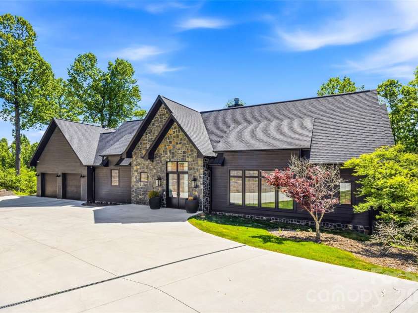 241 Tower Circle, Laurel Park, NC 28739.  MLS# CAR4346762, YatesRealty ID 2892. Modern mountain exterior with stone accents, dramatic rooflines, covered entry, and three-car garage.