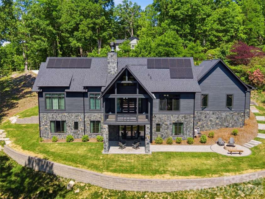 241 Tower Circle, Laurel Park, NC 28739.  MLS# CAR4346762, YatesRealty ID 2892. Rear elevation with expansive windows, covered deck, lower patio, and tiered outdoor living space.