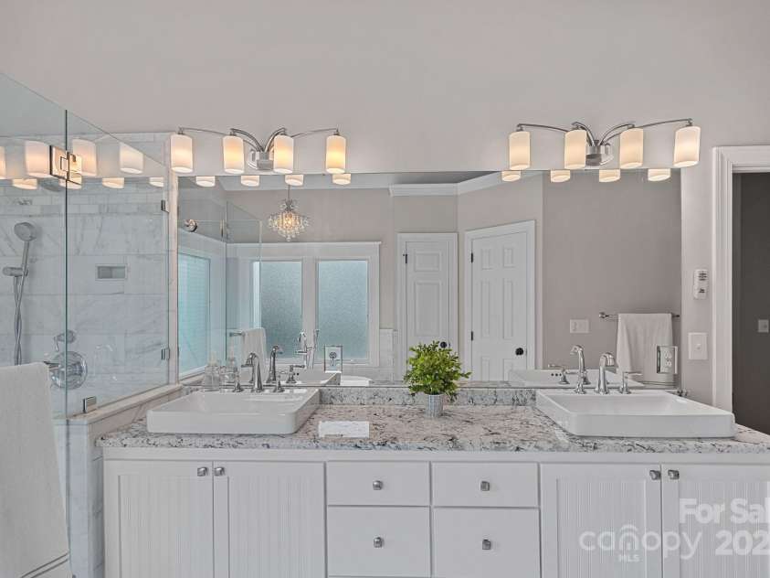 17308 Players Ridge Drive, Cornelius, NC 28031.  MLS# CAR4261359, YatesRealty ID 28986. The primary, spa-like bath has gorgeous granite countertops, a marble walk-in shower, free standing soaking tub and high ceilings.  It's quiet luxury and you'll love it!