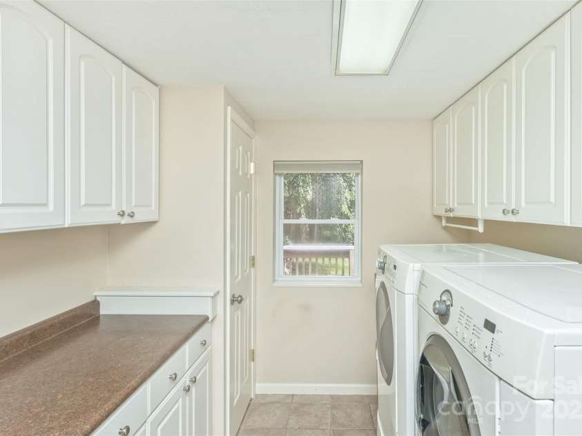 15 Beaverdam Knoll Road, Asheville, NC 28804.  MLS# CAR4283730, YatesRealty ID 29131. Located off the garage foyer, just a few steps from both the kitchen and sunroom, the laundry room has ample storage space including a closet that is accessible from both the laundry room and the sunroom.