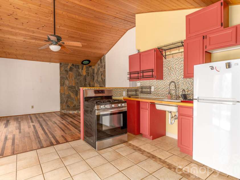 295 Richmond Road, Bakersville, NC 28705.  MLS# CAR4387768, YatesRealty ID 29139. Kitchen & living room area with unique wood floor and stone hearth.