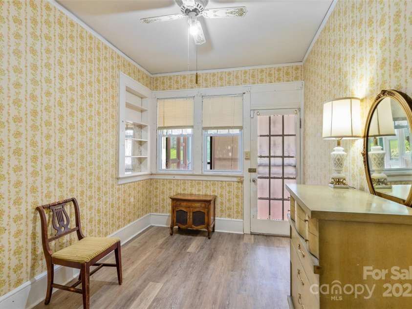 23 & 25 Oteen Park Place, Asheville, NC 28805.  MLS# CAR4287838, YatesRealty ID 29157. The smaller of the two main level bedrooms in this home leads to a light-filled, common enclosed covered patio that overlooks the backyard.