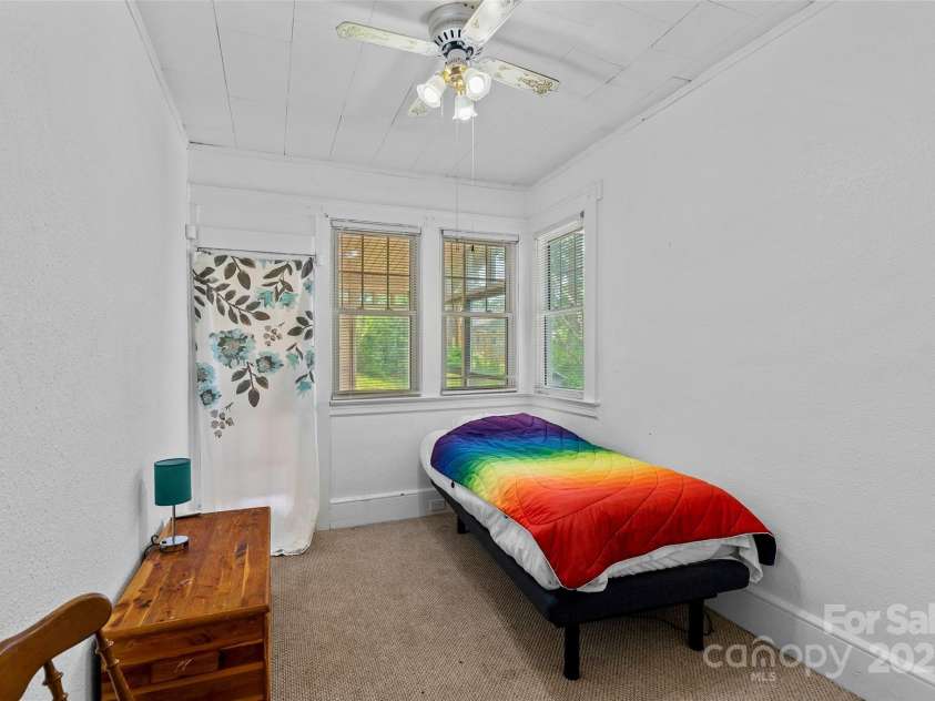 23 & 25 Oteen Park Place, Asheville, NC 28805.  MLS# CAR4287838, YatesRealty ID 29157. This is the smaller of the two bedrooms, and it would make a super office space. The door behind the floral print curtain leads to the enclosed patio, which overlooks the sweet backyard.
