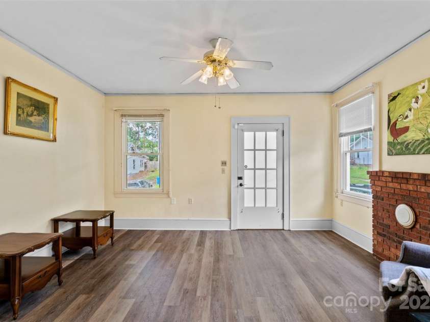 23 & 25 Oteen Park Place, Asheville, NC 28805.  MLS# CAR4287838, YatesRealty ID 29157. View of the front door entrance into the living room of unit 25. The original brick fireplace has been bricked over and remains as a part of the character of the home. The 9-foot ceilings and large, newer windows 