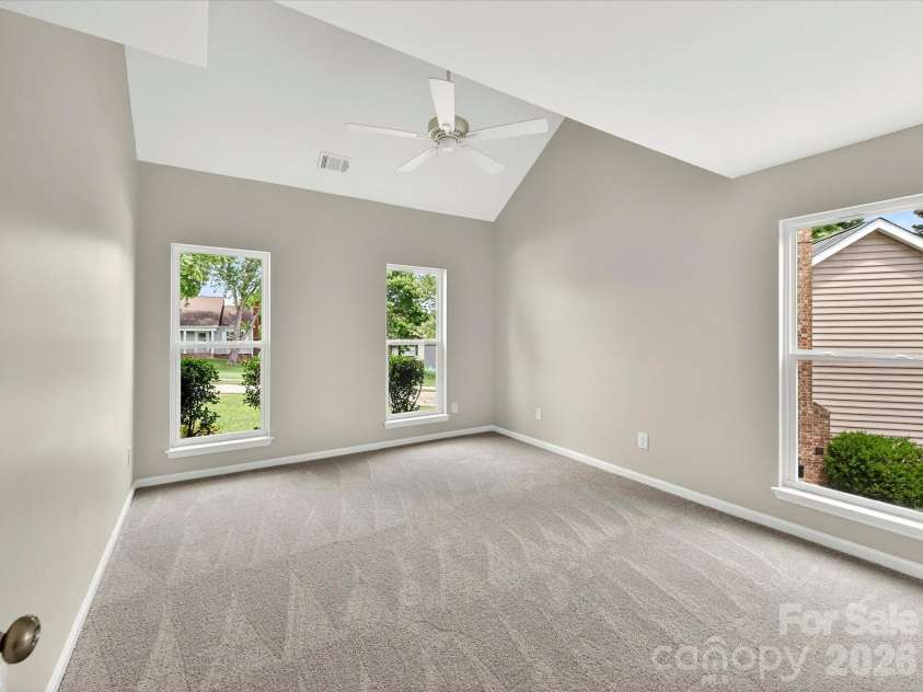 9716 Pernell Lane, Charlotte, NC 28213.  MLS# CAR4383771, YatesRealty ID 29190. Spacious primary bedroom features soaring vaulted ceilings, plush carpeting, abundant natural light, and an open, airy layout creating a peaceful retreat.