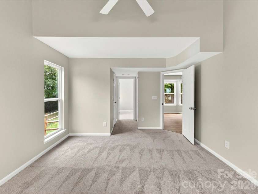 9716 Pernell Lane, Charlotte, NC 28213.  MLS# CAR4383771, YatesRealty ID 29190. Spacious primary bedroom features soaring vaulted ceilings, plush carpeting, abundant natural light, and an open, airy layout creating a peaceful retreat.