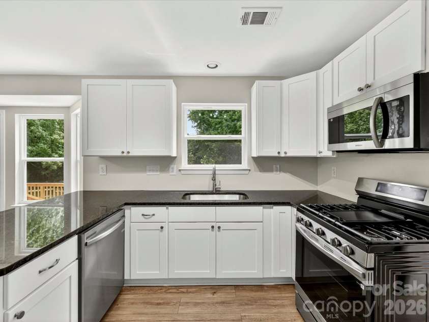 9716 Pernell Lane, Charlotte, NC 28213.  MLS# CAR4383771, YatesRealty ID 29190. Updated kitchen showcases sleek granite countertops, stainless steel appliances, modern white cabinetry, and a functional layout designed for both everyday living and entertaining.