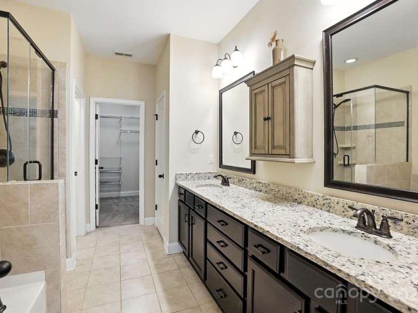 4128 La Crema Drive, Charlotte, NC 28214.  MLS# CAR4284944, YatesRealty ID 29298. Spa-like primary bath boasting dual vanities, tile flooring, garden tub, and tile walk-in shower
