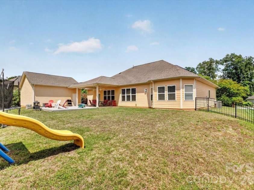 10585 Sweethaven Lane, Harrisburg, NC 28075.  MLS# CAR4356507, YatesRealty ID 29338. Backyard view which shows exactly how the roofing connects the 2.5 car garage with its exit door to the covered patio and thus the home.  This .39 size lot is big enough to add more outdoor play items which may even