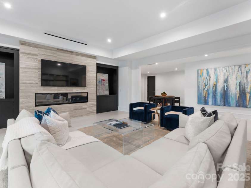 2116 Woodhaven Road, Charlotte, NC 28211.  MLS# CAR4186147, YatesRealty ID 2938. Lower level living area with linear modern fireplace, custom glass display case and leading out to lower level covered patio