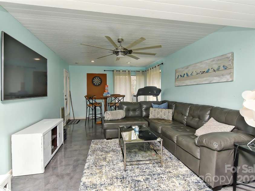 51 Old Post Road, Lake Wylie, SC 29710.  MLS# CAR4207674, YatesRealty ID 2950. The finished family-living room in basement w/concrete stamped flooring, wood ceilings, ceiling fan w/light and exterior door leading to covered back patio that over looks Lake Wylie!