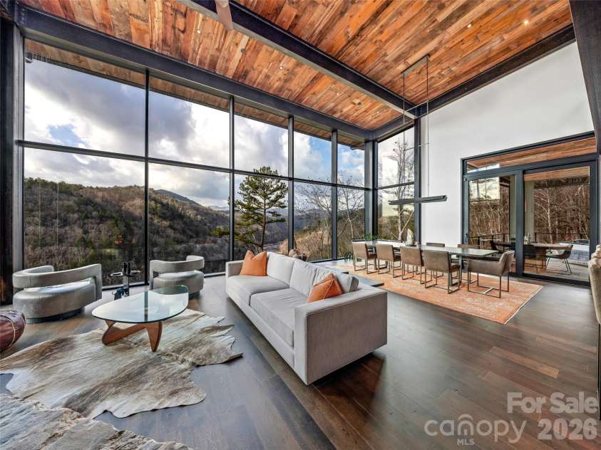 112 Moon Shadow Lane, Marshall, NC 28753.  MLS# CAR4332984, YatesRealty ID 2969. Dramatic floor to ceiling windows with ever changing views of the sky and river make this living area the ideal spot to gather. Wander through the sliding doors into the screened porch area.