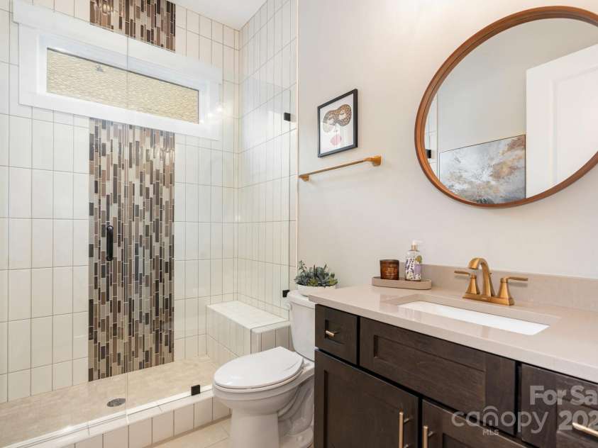 21016 Molly Harper Drive, Cornelius, NC 28031.  MLS# CAR4320388, YatesRealty ID 29705. Guest bath with upgraded light filled frameless shower featuring a transom window and custom tilework