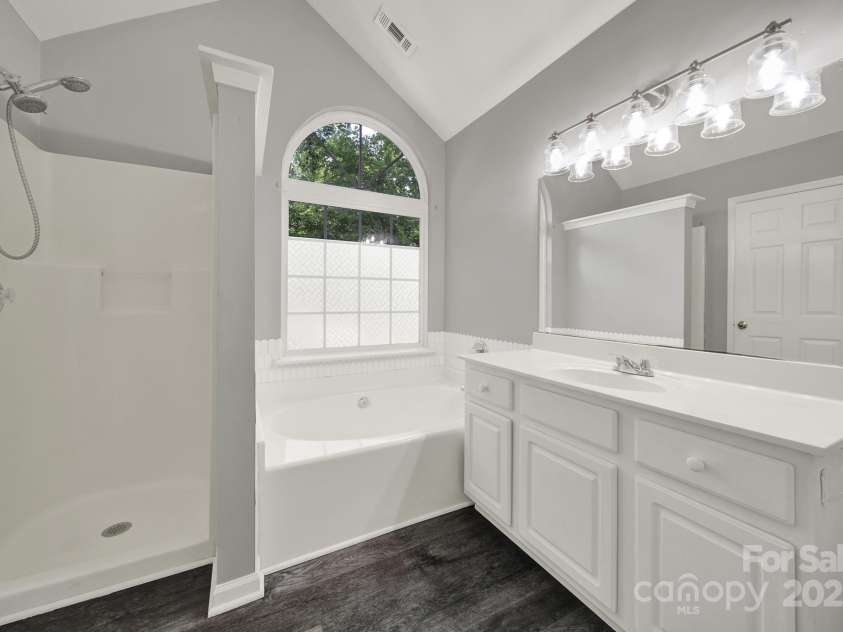 7801 Bella Vista Court, Charlotte, NC 28216.  MLS# CAR4285247, YatesRealty ID 29767. Another view of Primary Bath showing large window, vaulted ceiling, and neutral paint.