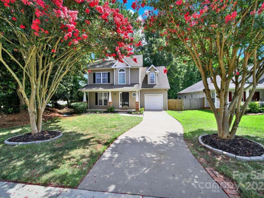 7801 Bella Vista Court, Charlotte, NC 28216.  MLS# CAR4285247, YatesRealty ID 29767. Street view showing blooming crepe myrtles, long driveway, and 1 car garage.