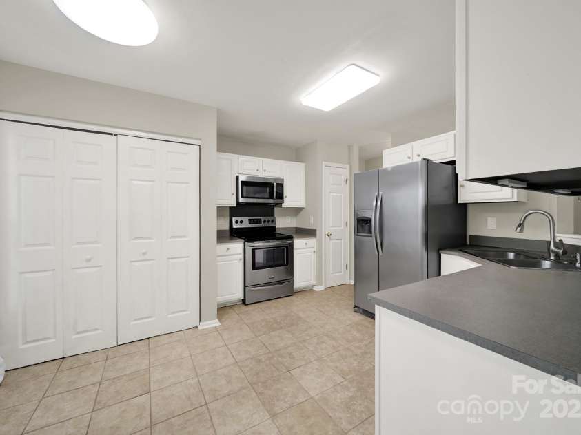 7801 Bella Vista Court, Charlotte, NC 28216.  MLS# CAR4285247, YatesRealty ID 29767. View into kitchen from Dining Room showing tile flooring, SS Appliances, Laundry area, and bright views.