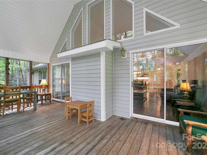 557 Country Club Estates Drive, Sapphire, NC 28774.  MLS# CAR4302980, YatesRealty ID 2977. Back deck / porch is right behind the fireplace wall in the great room. You can see dinner being prepared in the kitchen.