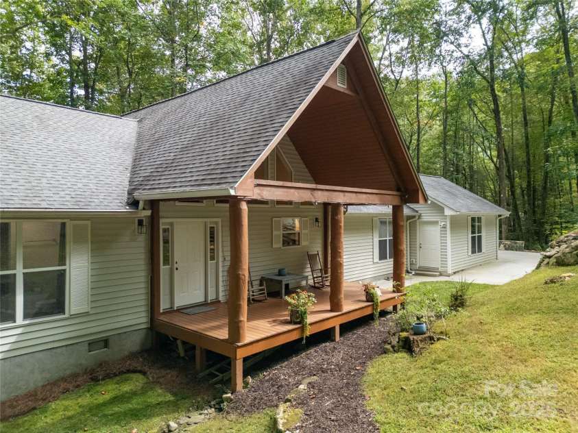 557 Country Club Estates Drive, Sapphire, NC 28774.  MLS# CAR4302980, YatesRealty ID 2977. House Front Porch and Detached Garage Door, as seen from the firepit. Small yard of green grass in front.