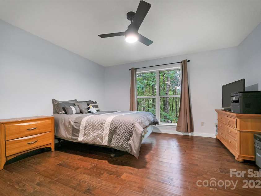 557 Country Club Estates Drive, Sapphire, NC 28774.  MLS# CAR4302980, YatesRealty ID 2977. The 3rd, rear, bedroom has the same privacy and treetops view as the primary bedroom on the other side of the house. Beautiful wood floors throughout!