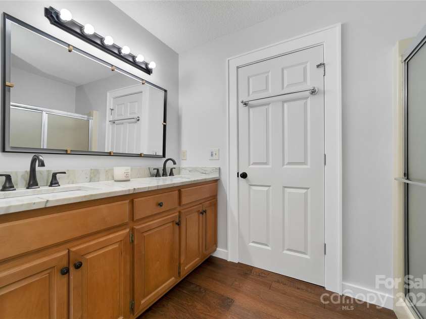 557 Country Club Estates Drive, Sapphire, NC 28774.  MLS# CAR4302980, YatesRealty ID 2977. The primary en-suite bathroom is quite stylish and has a double vanity. The beautiful wooden floors continue throughout this house.
