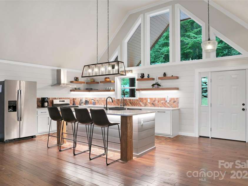 557 Country Club Estates Drive, Sapphire, NC 28774.  MLS# CAR4302980, YatesRealty ID 2977. This kitchen area is also part of the great room features a large island and two separate sinks.. Lots of natural light throughout with big upper window walls on both sides!