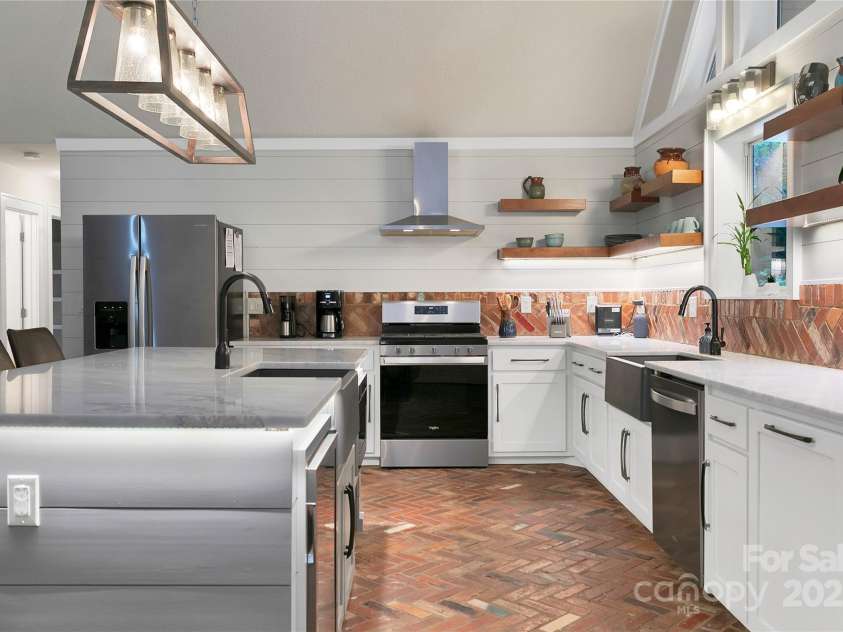 557 Country Club Estates Drive, Sapphire, NC 28774.  MLS# CAR4302980, YatesRealty ID 2977. This kitchen features a large island and two separate sinks. Lots of natural light! Very unique brick floor and backsplash to match! Stainless Steel Appliances throughout!