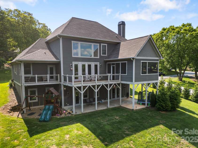 19 Carrolls Place Court, Mills River, NC 28759.  MLS# CAR4282064, YatesRealty ID 29890. Back of property, displaying the screened porch, exposed deck, primary bedroom's private covered deck, and covered patio from the walk-out basement