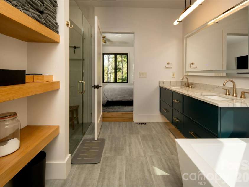 42 Spring Cove Road, Asheville, NC 28804.  MLS# CAR4246585, YatesRealty ID 29948. Another view of the ensuite bath.  Custom floating wood shelves on left and double vanity with LED mirror on right.