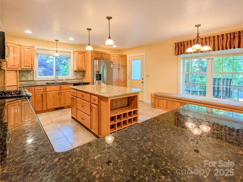 355 Rosewood Lane, Burnsville, NC 28714.  MLS# CAR4326302, YatesRealty ID 30113. Come inside to find the spacious chef's kitchen with granite countertops, plentiful cabinetry/storage, kitchen island with additional storage & built-in wine rack, the bench even opens up for additional storage & more! 