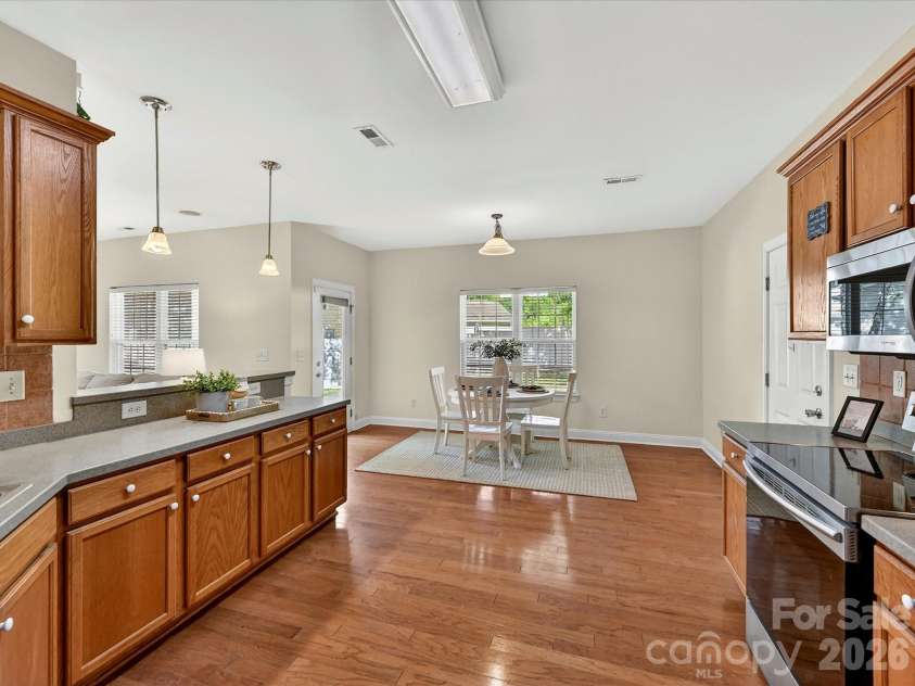 10507 Glenmeade Road, Cornelius, NC 28031.  MLS# CAR4391607, YatesRealty ID 30154. Spacious kitchen offers abundant cabinetry, expansive solid surface counters, stainless steel appliances, hardwood flooring, and a seamless connection to the breakfast area and main living spaces.