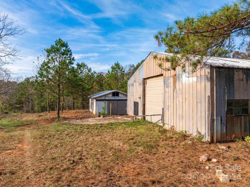 152 Long Branch Road, Chesnee, SC 29323.  MLS# CAR4204540, YatesRealty ID 302. Additional smaller workship just beyond the large one. Cleared lane next to fence on left allows access by vehicles. Look closely on the left, there is a concrete riser that looks like it may have been drainage or a septi