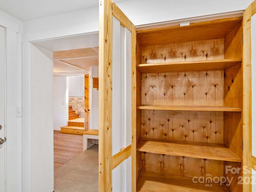 86 Chestnut Hill Road, Gerton, NC 28735.  MLS# CAR4213931, YatesRealty ID 3024. A built-in pantry with wooden shelving and charming barn-style doors. This offers practical storage options while maintaining a rustic and warm aesthetic.