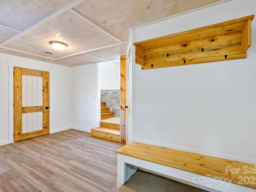 86 Chestnut Hill Road, Gerton, NC 28735.  MLS# CAR4213931, YatesRealty ID 3024. A second downstairs entrance leads to a cozy mudroom with built-in wooden benches and hooks for convenient storage. This functional space is perfect for keeping outdoor gear organized and tidy, ideal for busy households.