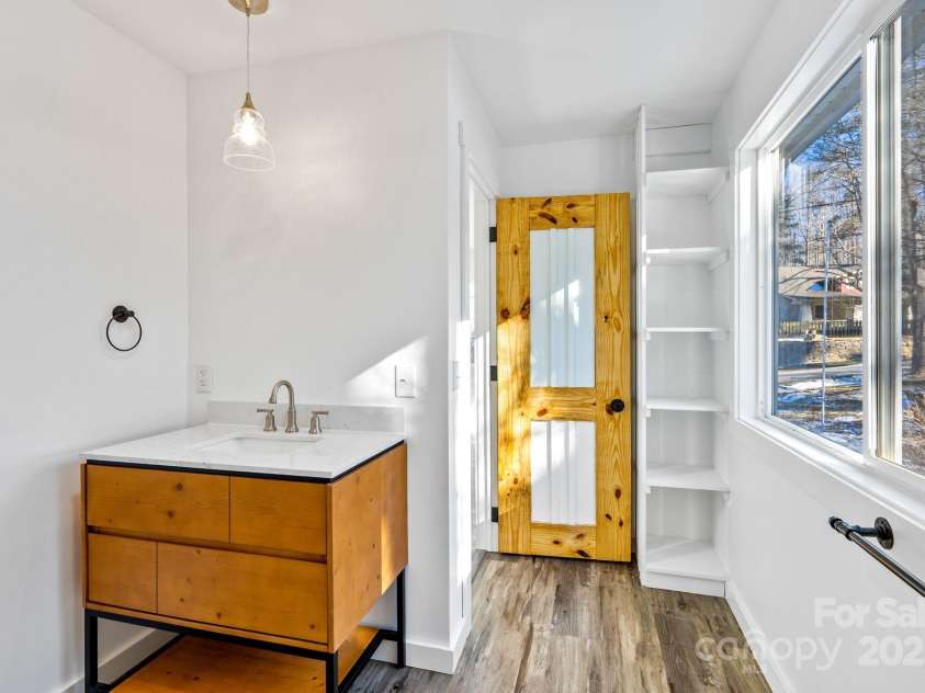 86 Chestnut Hill Road, Gerton, NC 28735.  MLS# CAR4213931, YatesRealty ID 3024. A stylish vanity with solid surface countertop and modern fixtures. The natural wood door and built-in shelving add functional and nature-inspired aesthetics to the space.