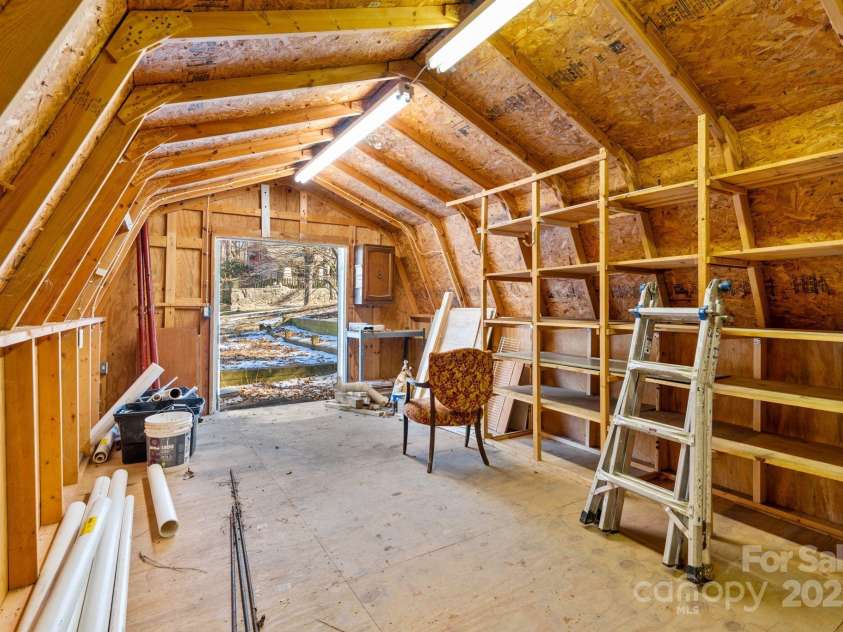 86 Chestnut Hill Road, Gerton, NC 28735.  MLS# CAR4213931, YatesRealty ID 3024. A view from inside the outbuilding shows wide double doors that open to the outdoors, making it easy to move larger items in and out. The well-lit interior ensures functionality throughout the year.