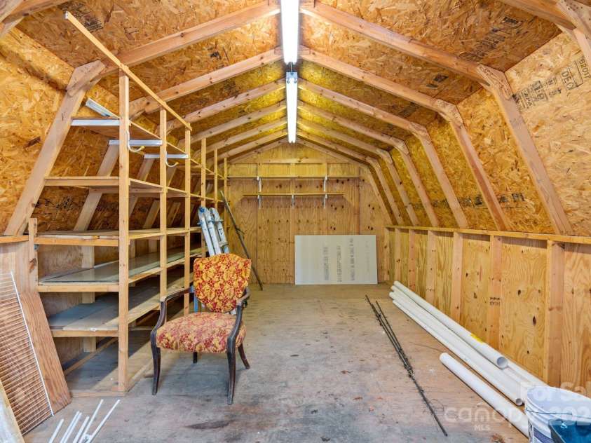 86 Chestnut Hill Road, Gerton, NC 28735.  MLS# CAR4213931, YatesRealty ID 3024. Inside the outbuilding, extensive built-in shelving offers functional organization for projects or storage needs. The vaulted ceiling adds a sense of spaciousness and utility.