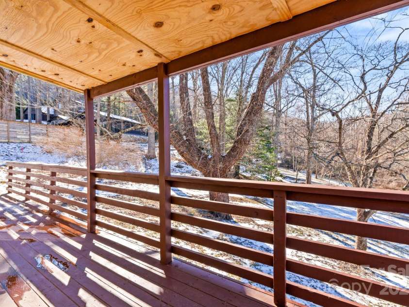 86 Chestnut Hill Road, Gerton, NC 28735.  MLS# CAR4213931, YatesRealty ID 3024. The covered section of the deck offers protection from the elements while maintaining a connection to the outdoors. The warm wood tones and scenic views make this a perfect spot for a morning coffee or evening gatherings