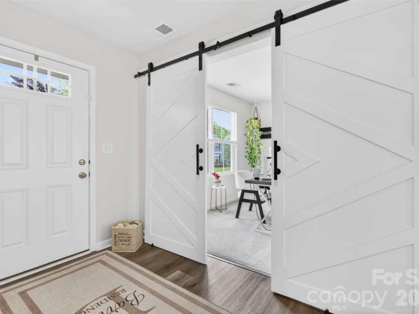 113 Browband Street, Troutman, NC 28166.  MLS# CAR4391440, YatesRealty ID 30536. Versatile flex space just off the front entry featuring stylish sliding barn doors, ideal as a home office, sitting room, study, or playroom.Photo 9 — Main Level BedroomConvenient main-level bedroom tucked toward the re
