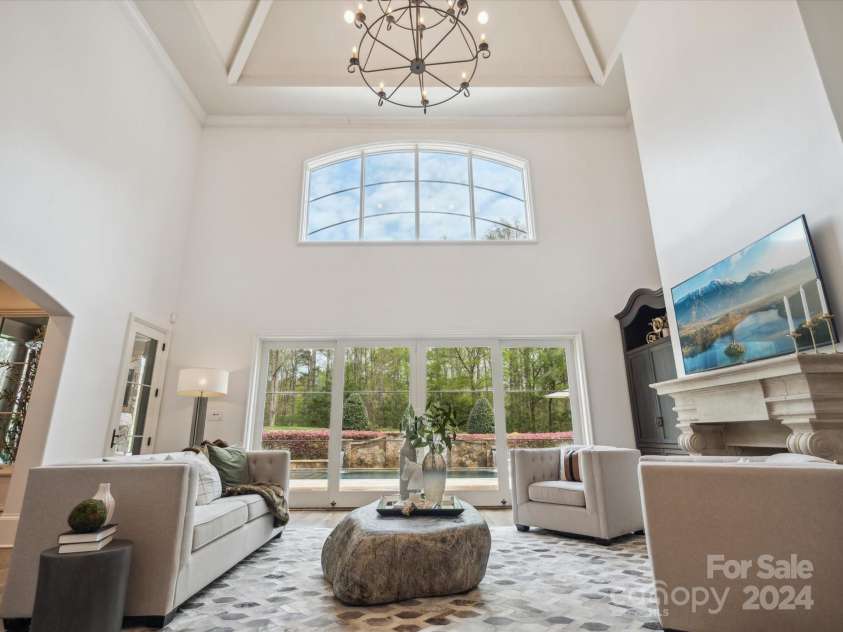 9044 Island Point Road, Charlotte, NC 28278.  MLS# CAR4135509, YatesRealty ID 3075. Experience the grandeur of the main living room, boasting ceilings that soar over 20 feet, offering a breathtaking view of the opulent backyard pool and entertainment oasis